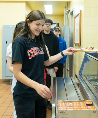 A young woman smiling while grabbing a tray of breakfast.